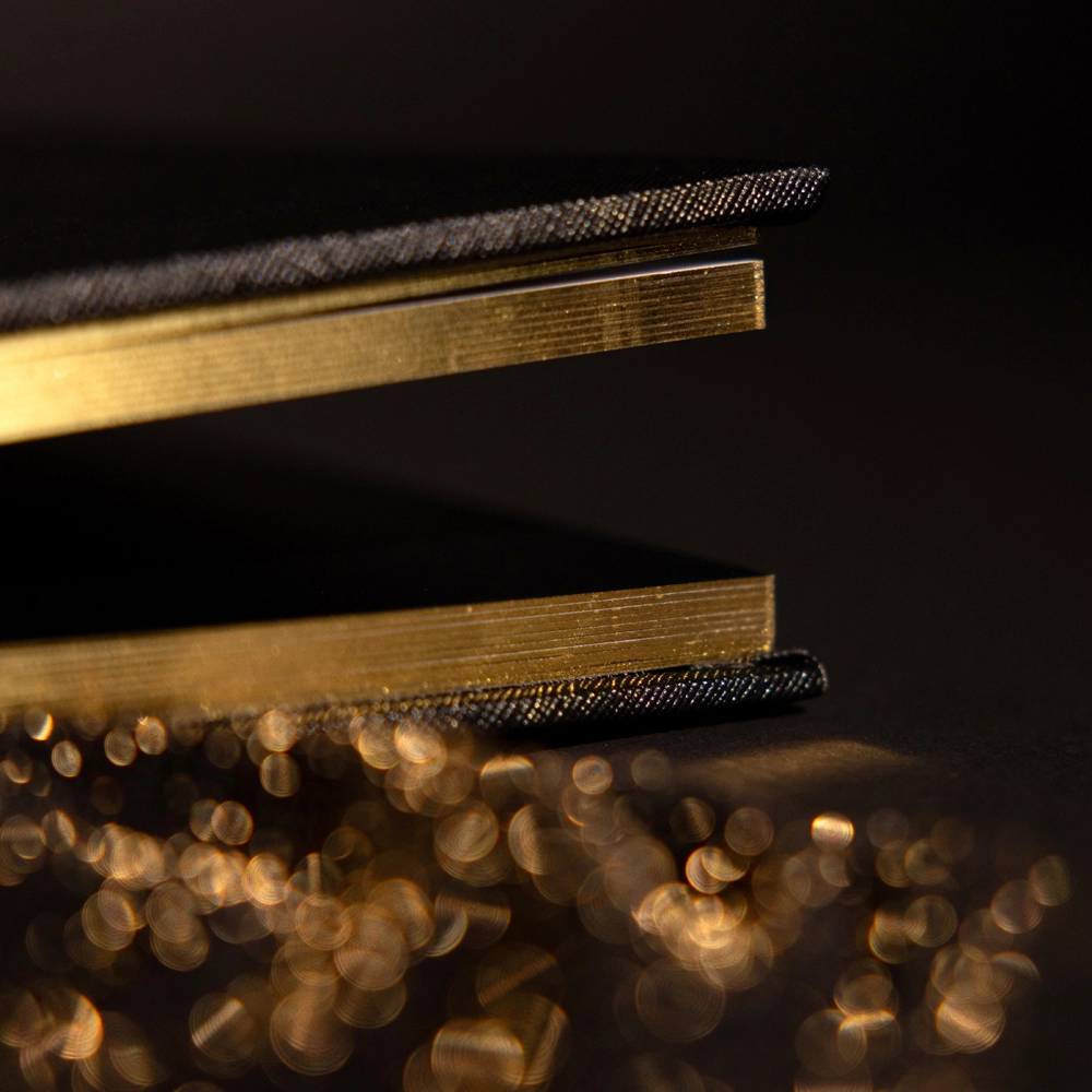 Close-up detail of a luxury boudoir photo album showing thick layflat pages with gold edging and premium craftsmanship.