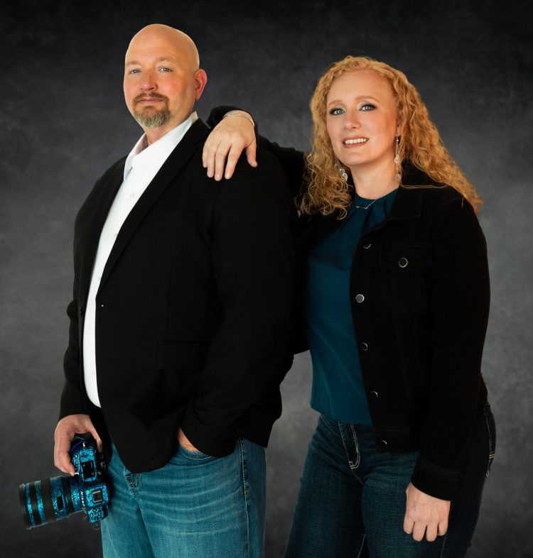 Chris Davis and Heidi Fritsche, founders of Primal Soul Boudoir in Rosenberg, Texas, standing together in a professional studio portrait with Chris holding a camera.